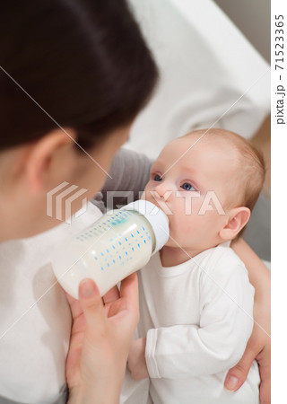 Woman holding a newborn baby in her arms and feeds him from a milk bottle. Woman holding a newborn baby in her arms and feeds him from a milk bottle. 71523365