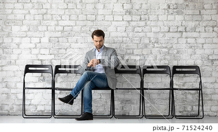 Young man job applicant sitting at company hall checking time Young man job applicant sitting at company hall checking time 71524240