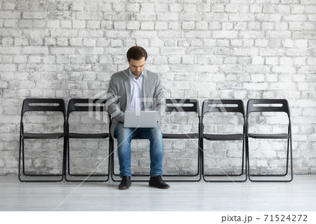 Concentrated millennial man applicant using laptop waiting for job interview Concentrated millennial man applicant using laptop waiting for job interview 71524272