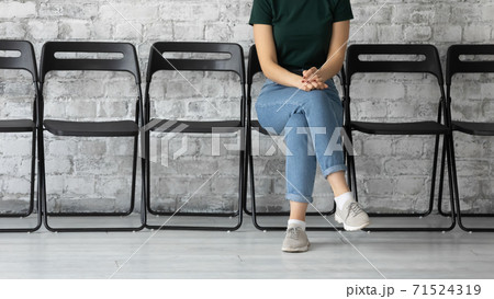Confident female job seeker sitting in corridor of temp agency 71524319