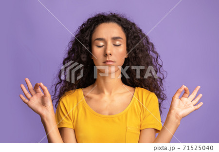 Zen. Calm lady meditating over purple background, keeping hands in mudra gesture 71525040