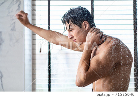 Handsome young man standing under hot water drops 71525046