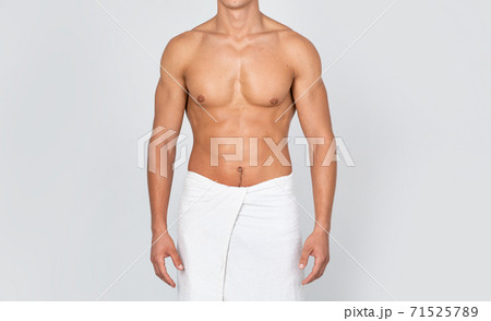 Unrecognizable shirtless young man standing wrapped in towel at studio Unrecognizable shirtless young man standing wrapped in towel at studio 71525789