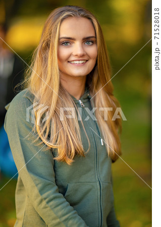 Confident young blond woman standing at park Confident young blond woman standing at park 71528018