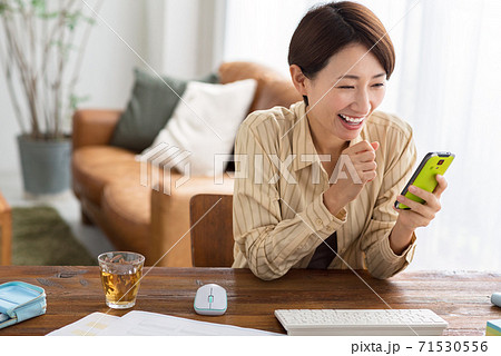 自宅でテレワーク中にスマホを確認するミドルのビジネスウーマン 自宅でテレワーク中にスマホを確認するミドルのビジネスウーマン 71530556