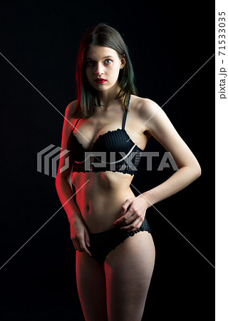 Cute brunette female model posing, wearing black underwear in dark studio 71533035