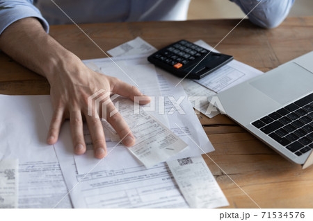 On desk lot of receipts calculator and laptop closeup view 71534576