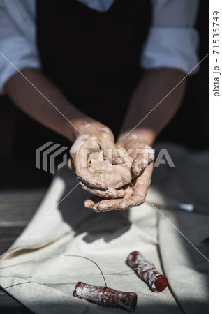 Close up of woman hands works with clay. Female potter kneads and moistens the clay before work. Close up of woman hands works with clay. Female potter kneads and moistens the clay before work. 71535749