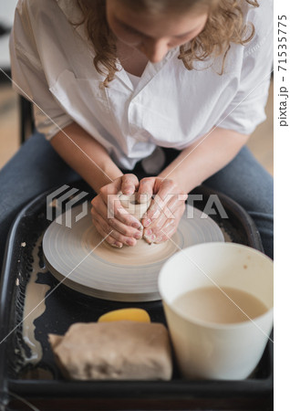 Woman working on potters wheel making dishes with their own hands. Close-up photo of dirty hands molding clay 71535775