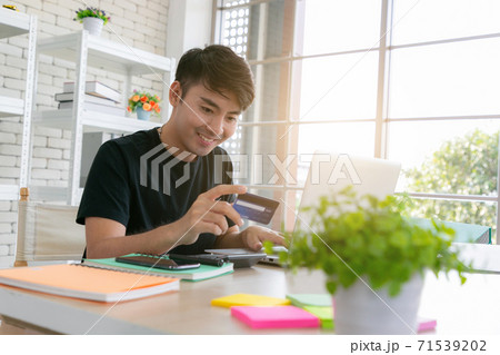 A man paying for online shopping using laptop and credit card. This image is illustrated the online payment concept via smartphone. A man paying for online shopping using laptop and credit card. This image is illustrated the online payment concept via smartphone. 71539202