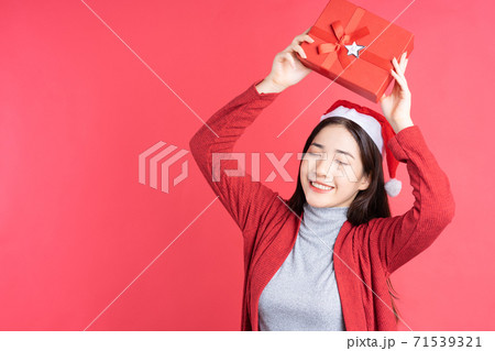 Beautiful Asian woman holding red gift box on red background 71539321