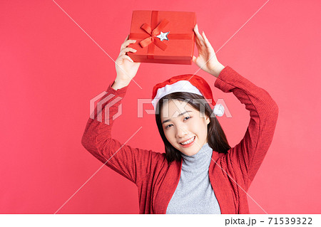 Beautiful Asian woman holding red gift box on red background 71539322