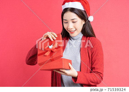 Beautiful Asian woman holding red gift box on red background Beautiful Asian woman holding red gift box on red background 71539324