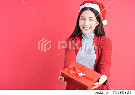 Beautiful Asian woman holding red gift box on red background 71539325