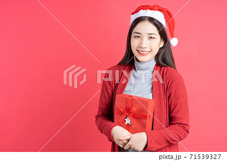 Beautiful Asian woman holding red gift box on red background 71539327