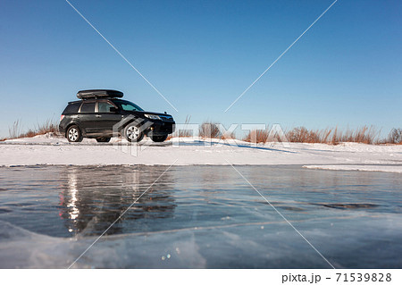 Subaru Forester with rooftop box at frozen lake ice. Subaru Forester with rooftop box at frozen lake ice. 71539828