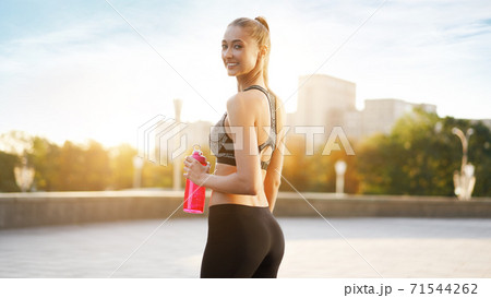Woman drink water red bottle after morning workout city background Woman drink water red bottle after morning workout city background 71544262