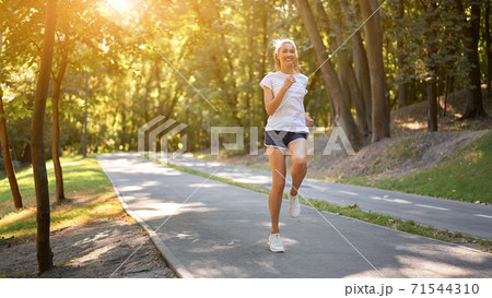 Woman running asphalt road summer park 71544310