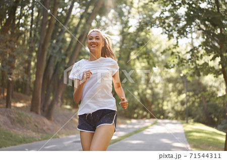 Woman running asphalt road summer park 71544311