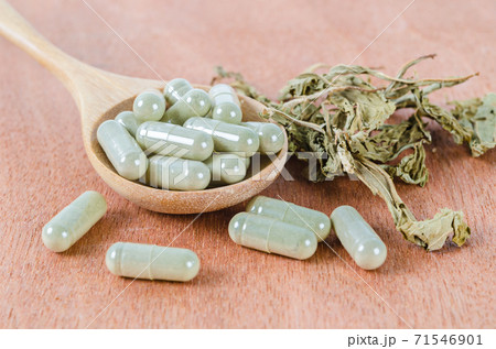 Herb medical capsules in wooden spoon with dry leaves herb. Herb medical capsules in wooden spoon with dry leaves herb. 71546901