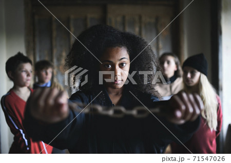 Portrait of mixed-race teenager girl with hands in chains indoors in abandoned building. Portrait of mixed-race teenager girl with hands in chains indoors in abandoned building. 71547026