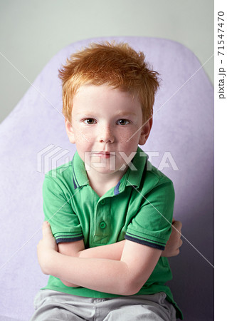 Cute red haired freckled little boy in green t-shirt waiting for doctor in medical office 71547470