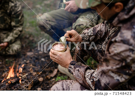 Picnic near Bonfire Hunter Opens Tin in Forest. Picnic near Bonfire Hunter Opens Tin in Forest. 71548423