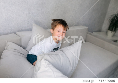 little boy having pillow fight on sofa at home 71549006