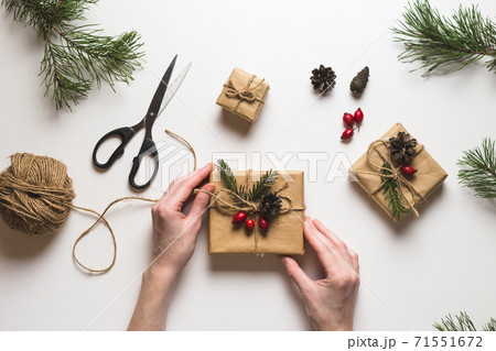 Christmas composition. Female hands keeping christmas gifts, pine branches, toys on white background. Flat lay, top view, copy space. Christmas composition. Female hands keeping christmas gifts, pine branches, toys on white background. Flat lay, top view, copy space. 71551672