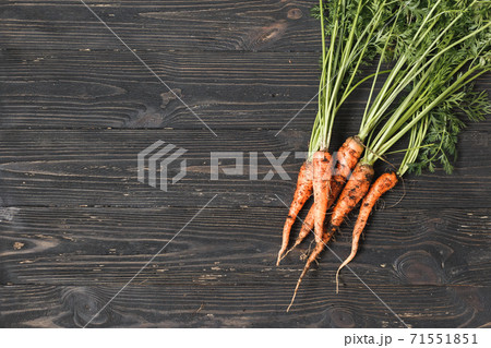 Bunch of ripe carrots on a black wooden background with space for text Bunch of ripe carrots on a black wooden background with space for text 71551851
