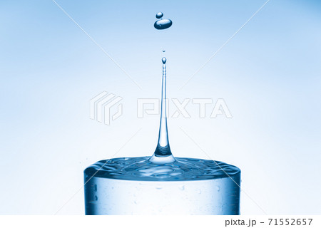 Water drop splashing into glass from isolated bright blue background Water drop splashing into glass from isolated bright blue background 71552657