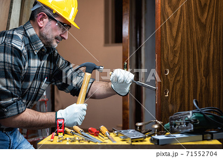 Carpenter at work repairs and installs the door lock. Carpentry. 71552704