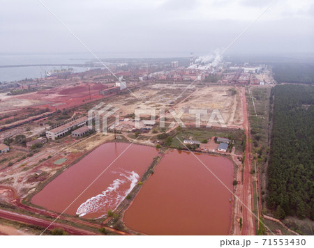 Aerial Bird eye Top View at Red Clay Pools With a Gateway Sluices Seethes: Spillway of a Clay Factory Aerial Bird eye Top View at Red Clay Pools With a Gateway Sluices Seethes: Spillway of a Clay Factory 71553430