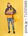 Food delivery smiling Caucasian young man in yellow jacket and with thermos bag on his shoulders on yellow background. Concept of Express food delivery in city, banner with space for text and slogan 71555689