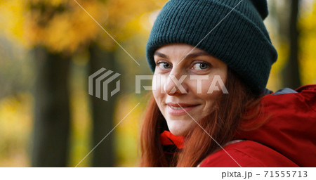 A young girl in warm clothes looks into the camera and smiles outside in cold weather A young girl in warm clothes looks into the camera and smiles outside in cold weather 71555713