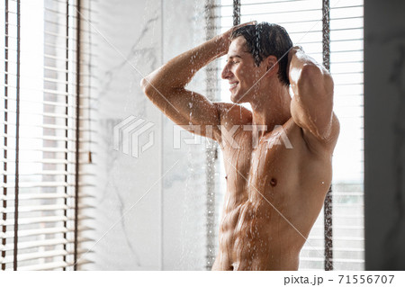 Charming young male model enjoying taking hot shower 71556707