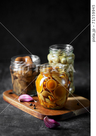 Glass jar with canned mushrooms. Fermented food on a dark table Glass jar with canned mushrooms. Fermented food on a dark table 71559945