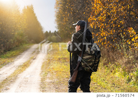 Hunter with a gun and a backpack Hunter with a gun and a backpack 71560574