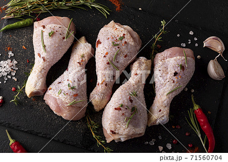 raw chicken drumsticks with spices and herbs on black board 71560704