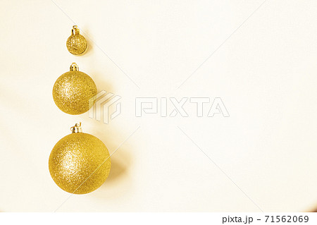 Three golden Christmas balls of different sizes are displayed in a row as a border on a white background. Copy space Three golden Christmas balls of different sizes are displayed in a row as a border on a white background. Copy space 71562069
