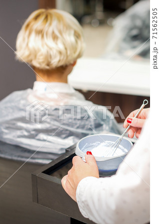 Hairdresser is preparing dye in container 71562505
