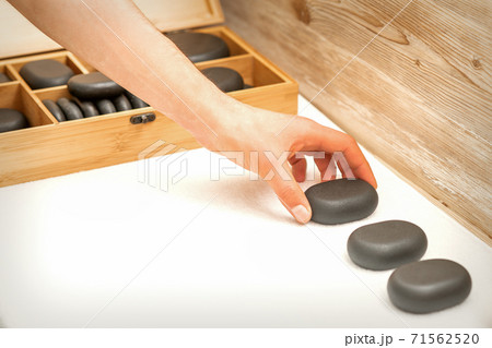 Masseur lays out massage stones Masseur lays out massage stones 71562520