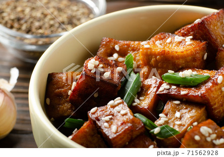 Close Up view at crispy fried tofu pieces with chives and sesame in clay dish 71562928