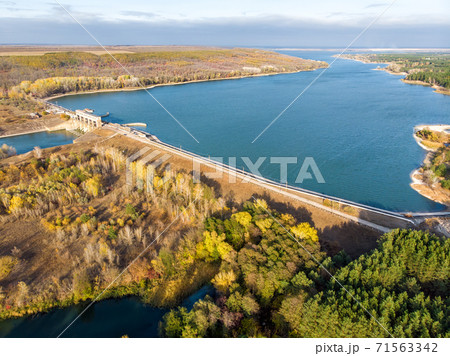 Aerial drone bird eye view of big artificial water storage reservoir on river Oskol with hydropower turbine electricity power generationplant. Natural ukrainian beautiful lake and forest landscape Aerial drone bird eye view of big artificial water storage reservoir on river Oskol with hydropower turbine electricity power generationplant. Natural ukrainian beautiful lake and forest landscape 71563342