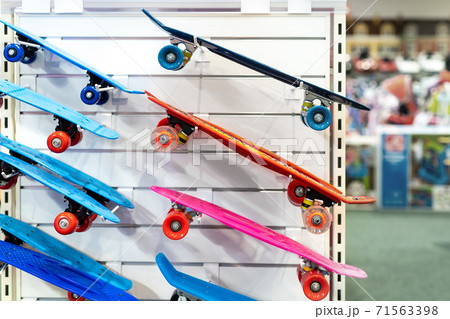 Many colorful plastic small skateboards toys hanged on store shop window display. Child sport and fun accessories. Children gift or present idea 71563398