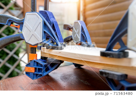 Joining wooden handmade box with clamps joiners after glueing. Different chisels, drills and pencils at craftsman workshop. DIY instruments on wood workbench. Workplace organization arrangement 71563480