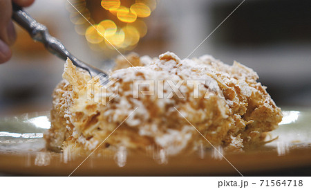 Tasty dessert. Slice of Napoleon cream cake, made from puff pastry, lies on a plate on a table in a restaurant 71564718