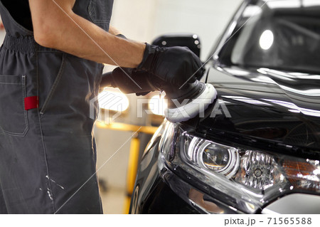 male hands with orbital polisher in auto repair shop 71565588