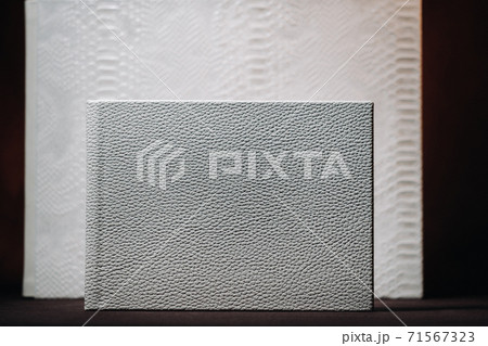Composition of photo books in natural white leather of different sizes. The white paper on a dark background. Composition of photo books in natural white leather of different sizes. The white paper on a dark background. 71567323