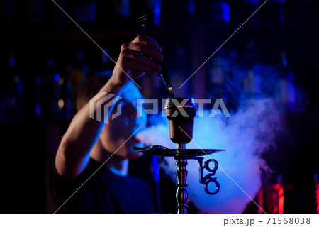 Man smoking traditional hookah pipe and exhaling smoke in hookah cafe. Man smoking traditional hookah pipe and exhaling smoke in hookah cafe. 71568038